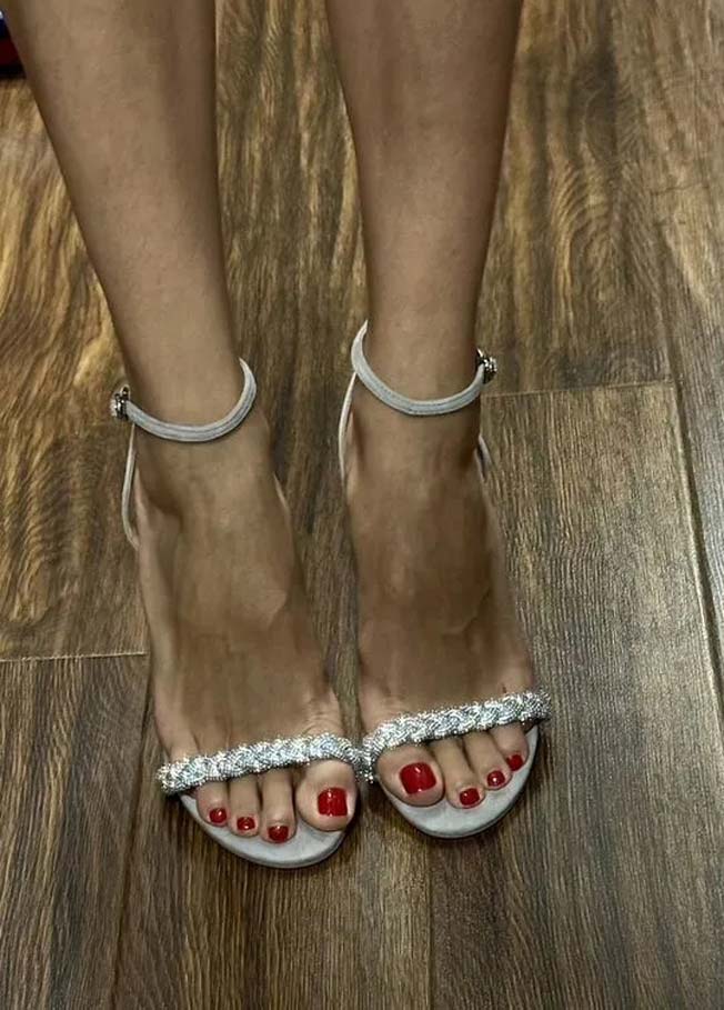 red pedicured feet on a white high heels sandals